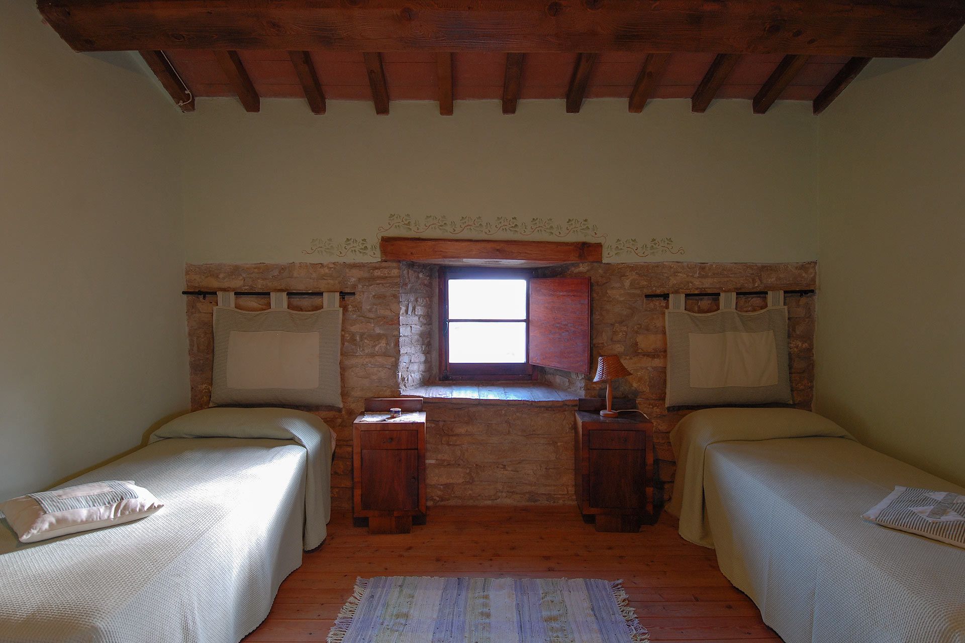 Une chambre avec deux lits simples, une petite table et une fenêtre.