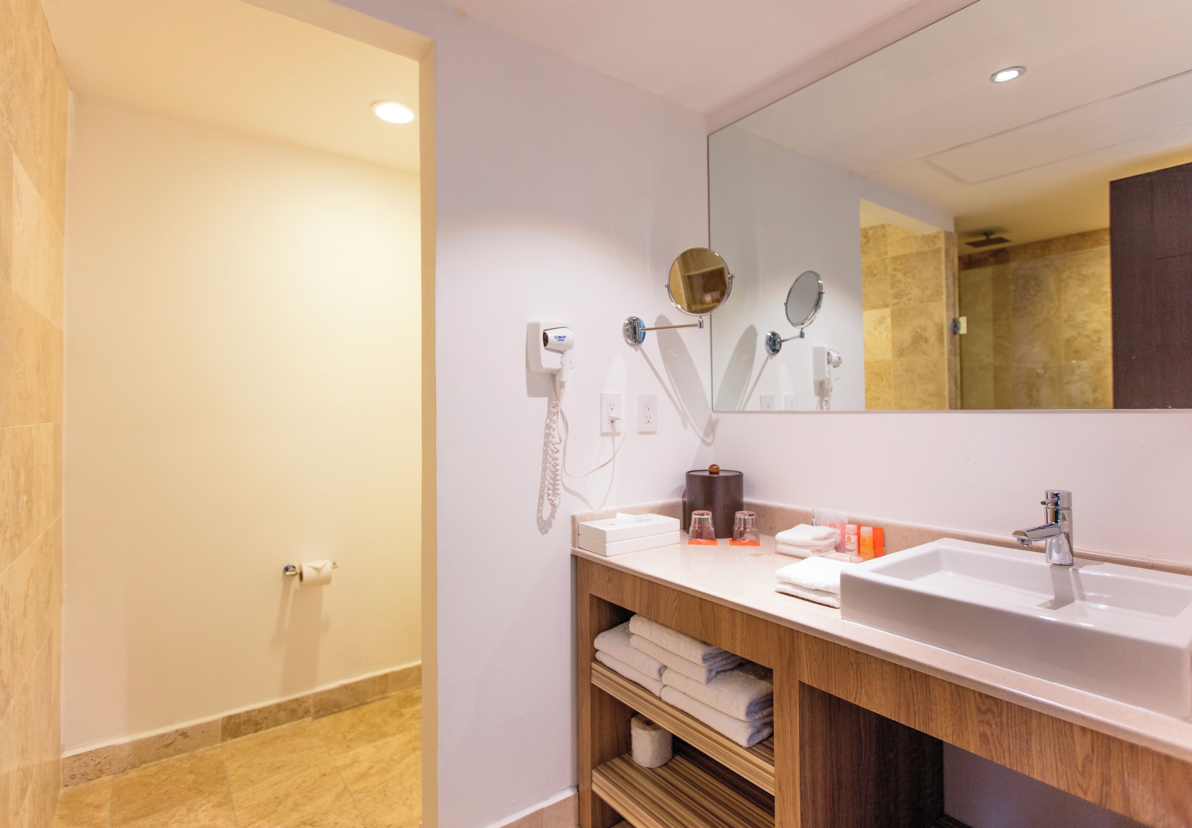 A modern bathroom with a large mirror, a sink, and a shower area.