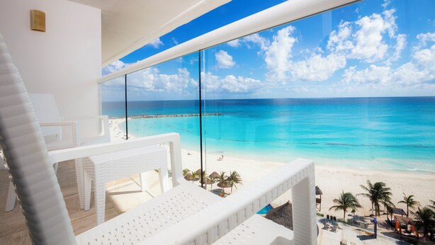 A beach view from a balcony with white wicker furniture and a clear blue sky. - Krystal Cancun All Inclusive (Cancun)