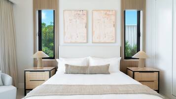 Une chambre d’hôtel avec un grand lit, deux tables de chevet, une fenêtre et deux tableaux abstraits accrochés au mur.