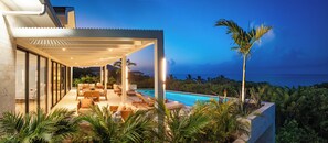 Un espace de détente extérieur moderne, doté d’une piscine, de sièges et offrant une vue sur l’océan.