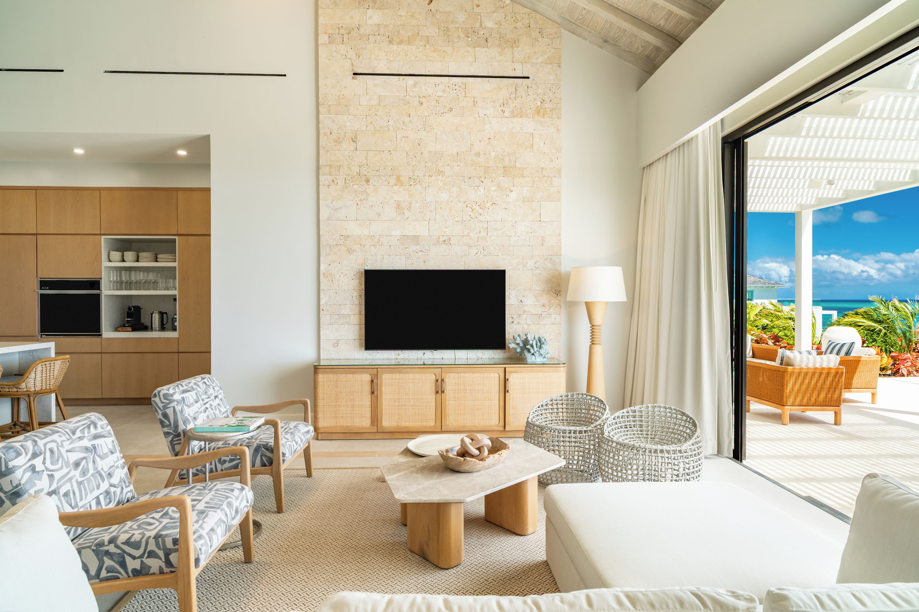 Een moderne woonkamer met een stenen openhaard, houten meubels en uitzicht op de oceaan.