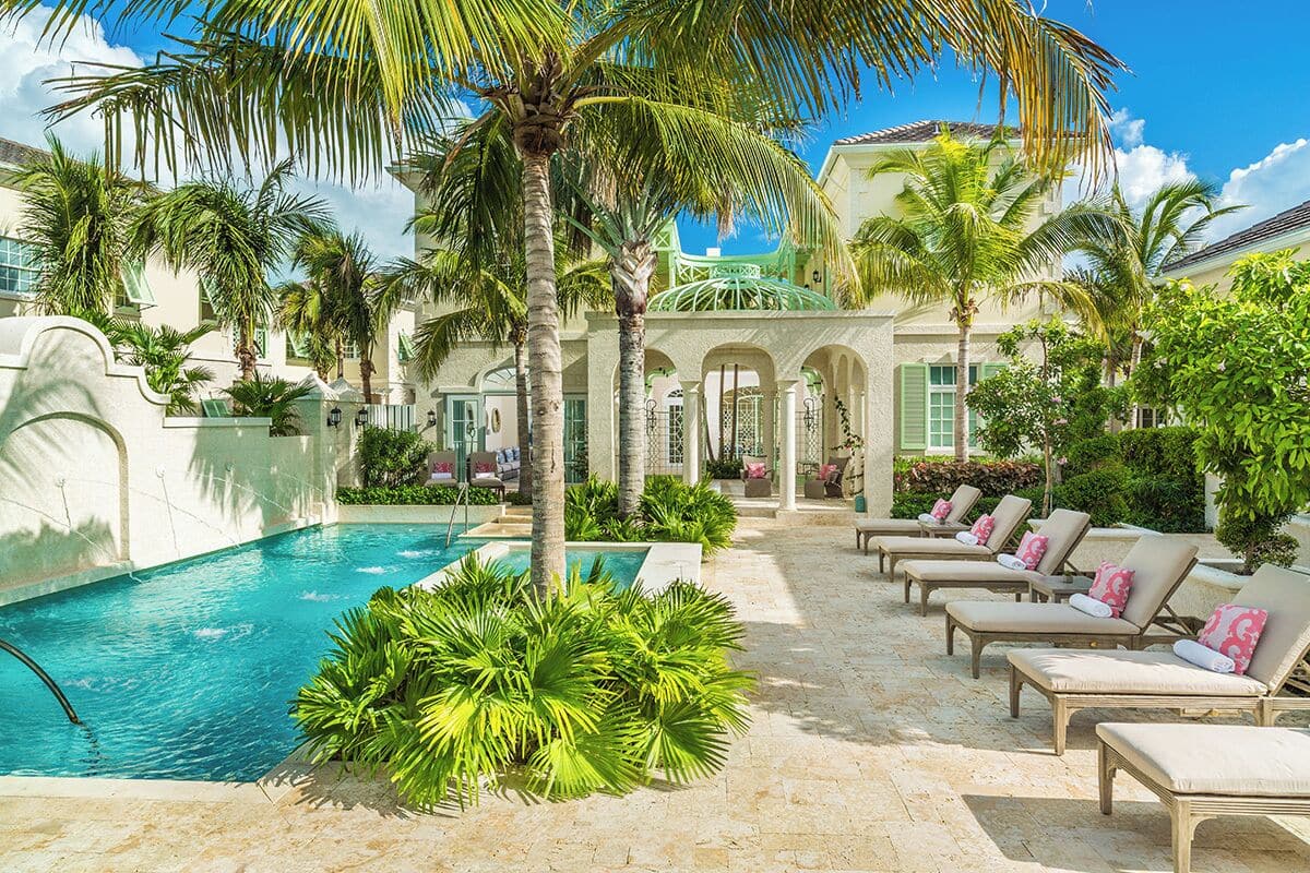 Un espace piscine avec des chaises longues et des palmiers.