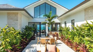 Une maison moderne dotée d’un patio aménagé avec du mobilier d’extérieur et une végétation luxuriante.