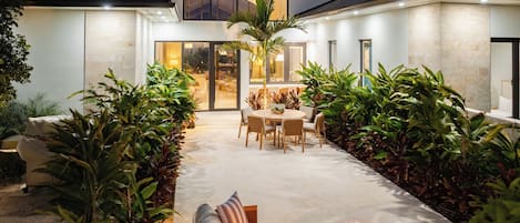A modern house with a patio area featuring a sofa, a dining table, and a fire pit.