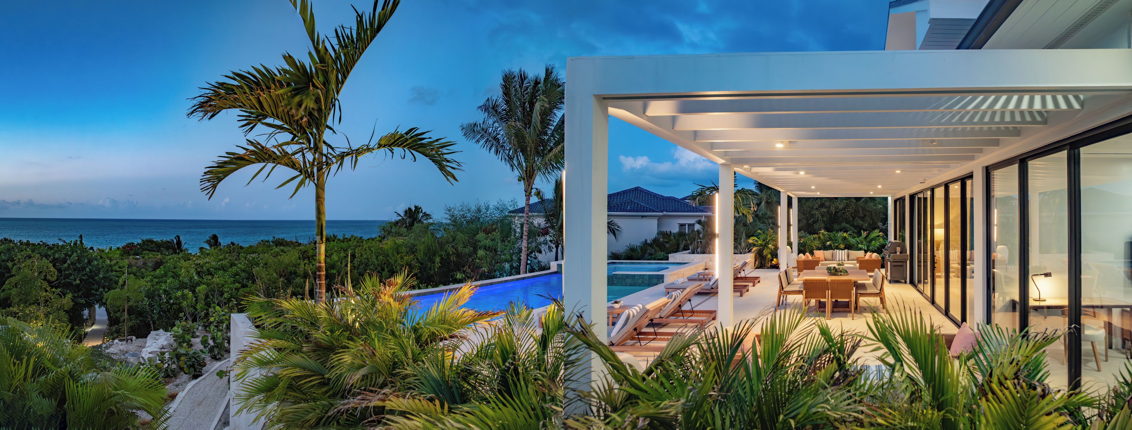Une maison moderne dotée d’une piscine, d’un espace salon extérieur et offrant une vue sur l’océan.