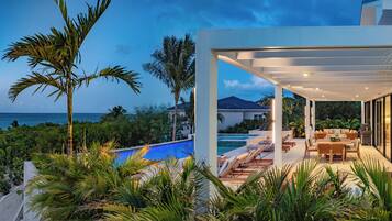 Une maison moderne dotée d’une piscine, d’un espace salon extérieur et offrant une vue sur l’océan.