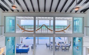 A modern interior with a glass balustrade overlooking a pool and ocean view. - Villas at Blue Mountain  (Providenciales)