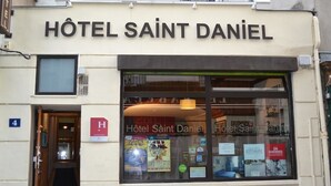 The exterior of Hôtel Saint Daniel with a clear entrance, a visible door, and a window displaying various posters and signs. - Hotel Saint Daniel (Nantes)
