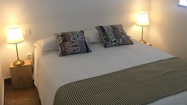 A bedroom with a bed, two wall-mounted mirrors, two bedside lamps, and patterned pillows. - Casa do Peso (Peso da Régua)