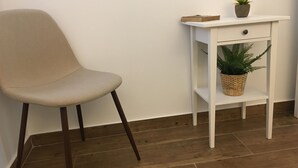 A beige chair, a white side table with a drawer, and a potted plant on the table. - Casa do Peso (Peso da Régua)