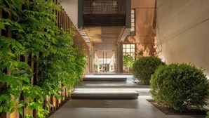 Un bâtiment moderne avec un chemin en béton bordé de verdure et une clôture en bois.