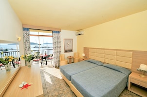 Habitación de hotel con una cama grande, un escritorio de madera, una silla y vista al mar.
