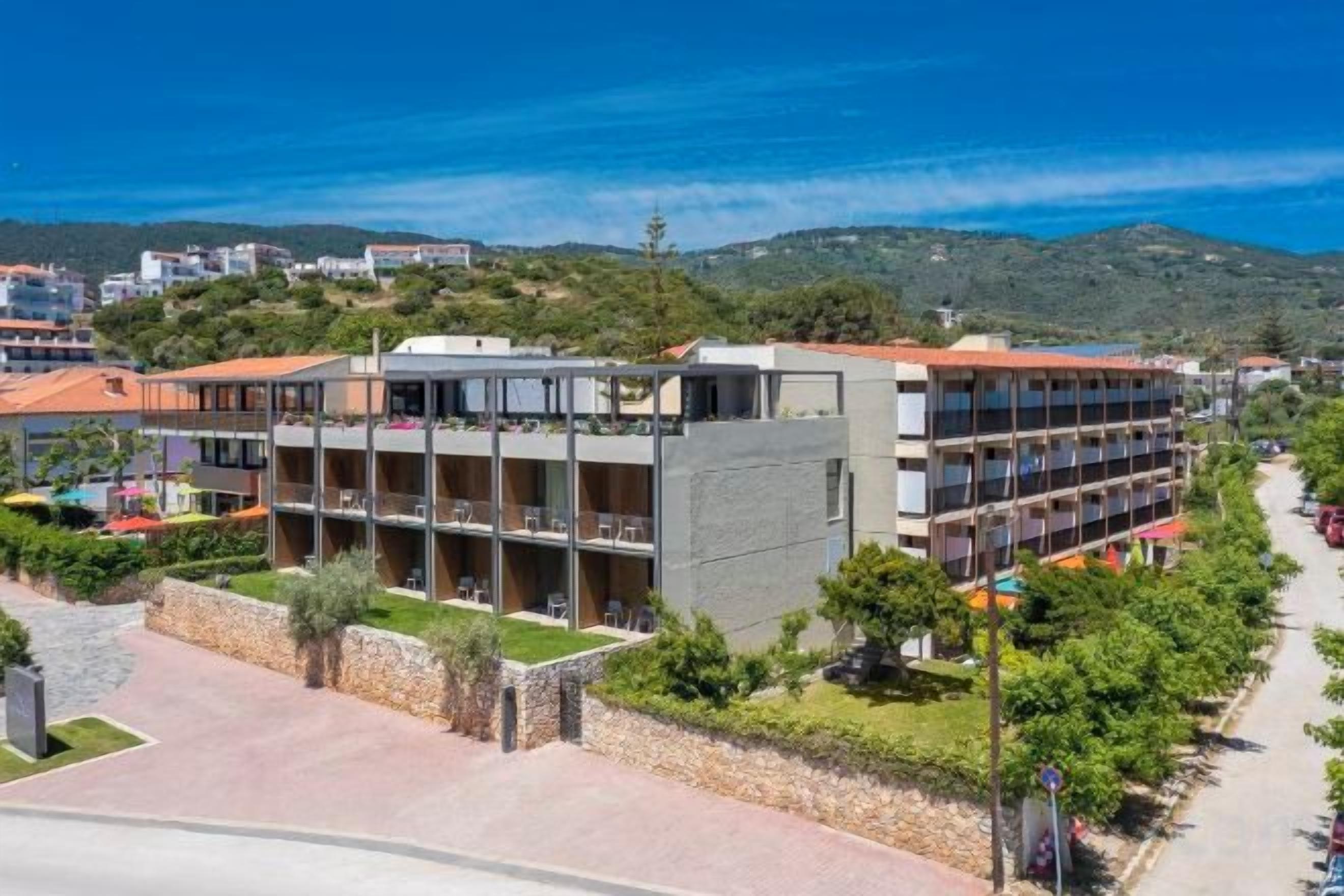 A multi-story hotel with balconies, a paved courtyard, and a view of the surrounding area.