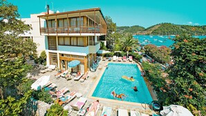 Un hôtel de deux étages doté d’une piscine, de chaises longues et offrant une vue sur la mer.
