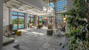 Un espace intérieur vaste et lumineux, doté de grandes fenêtres, d’un sol en pierre et de meubles modernes.