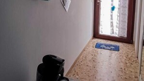 Un couloir étroit avec un plafond et des murs bleus, qui mène à une porte donnant sur un bâtiment à l’extérieur.