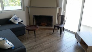 Un salon avec une cheminée, un canapé, un fauteuil et une table basse.