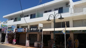 Une vue d’une rue bordée de différents commerces, notamment un salon de tatouage, une bijouterie et une boutique.