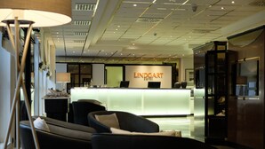 Una hall d'hotel moderna con scrivania della reception, area salotto e elementi decorativi.