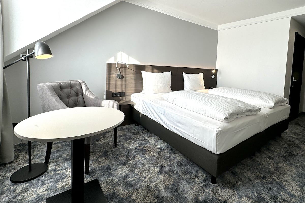 Ein modernes Hotelzimmer mit Bett, Stuhl, Tisch und Lampe.