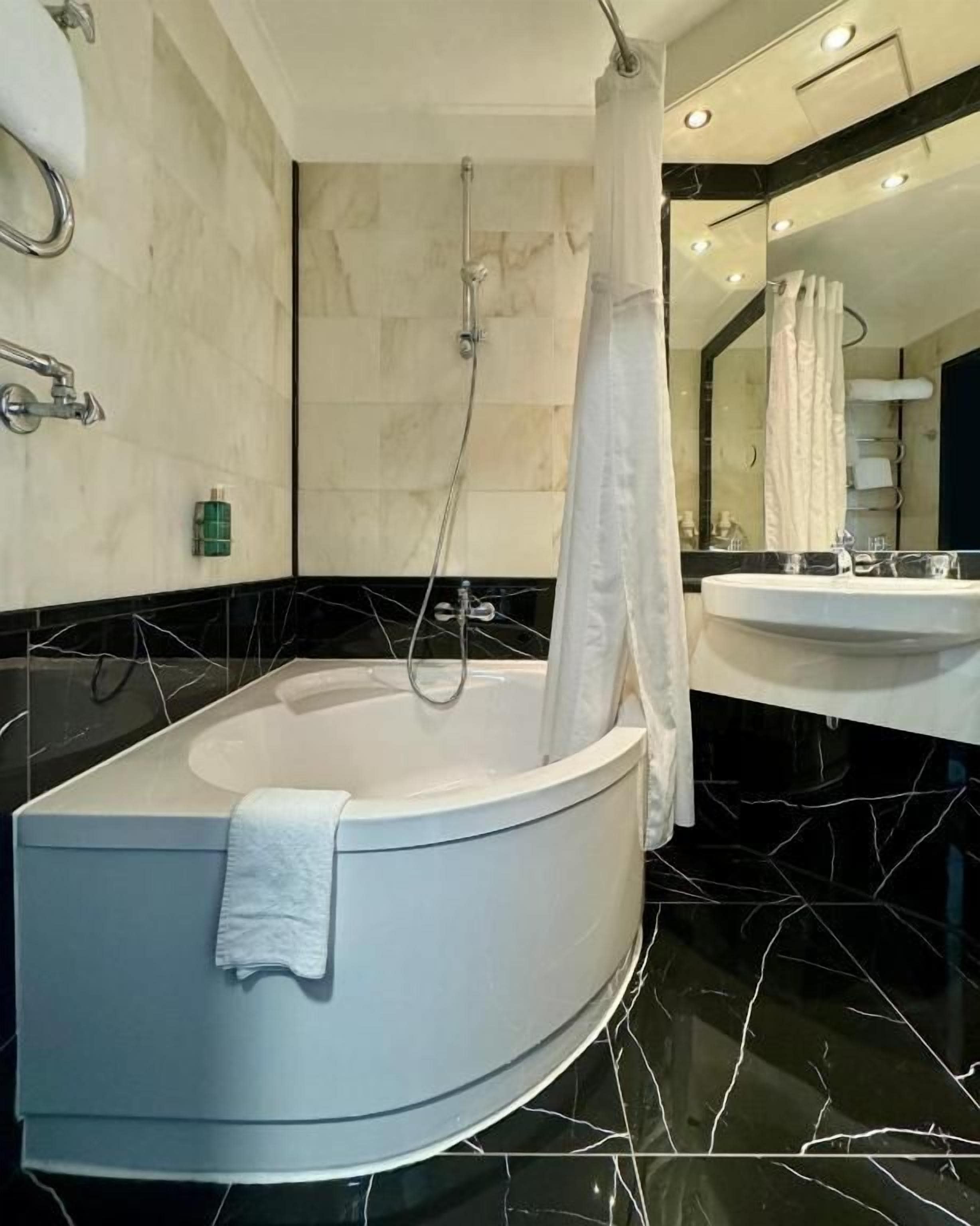 A modern bathroom with a freestanding bathtub, a large mirror, and a vanity with a sink.