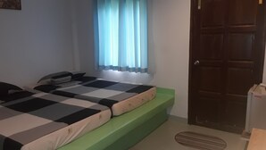 A bedroom with two beds, a window with curtains, a door, and a radiator. - Suanrimtarn Suanphung (Suan Phueng)