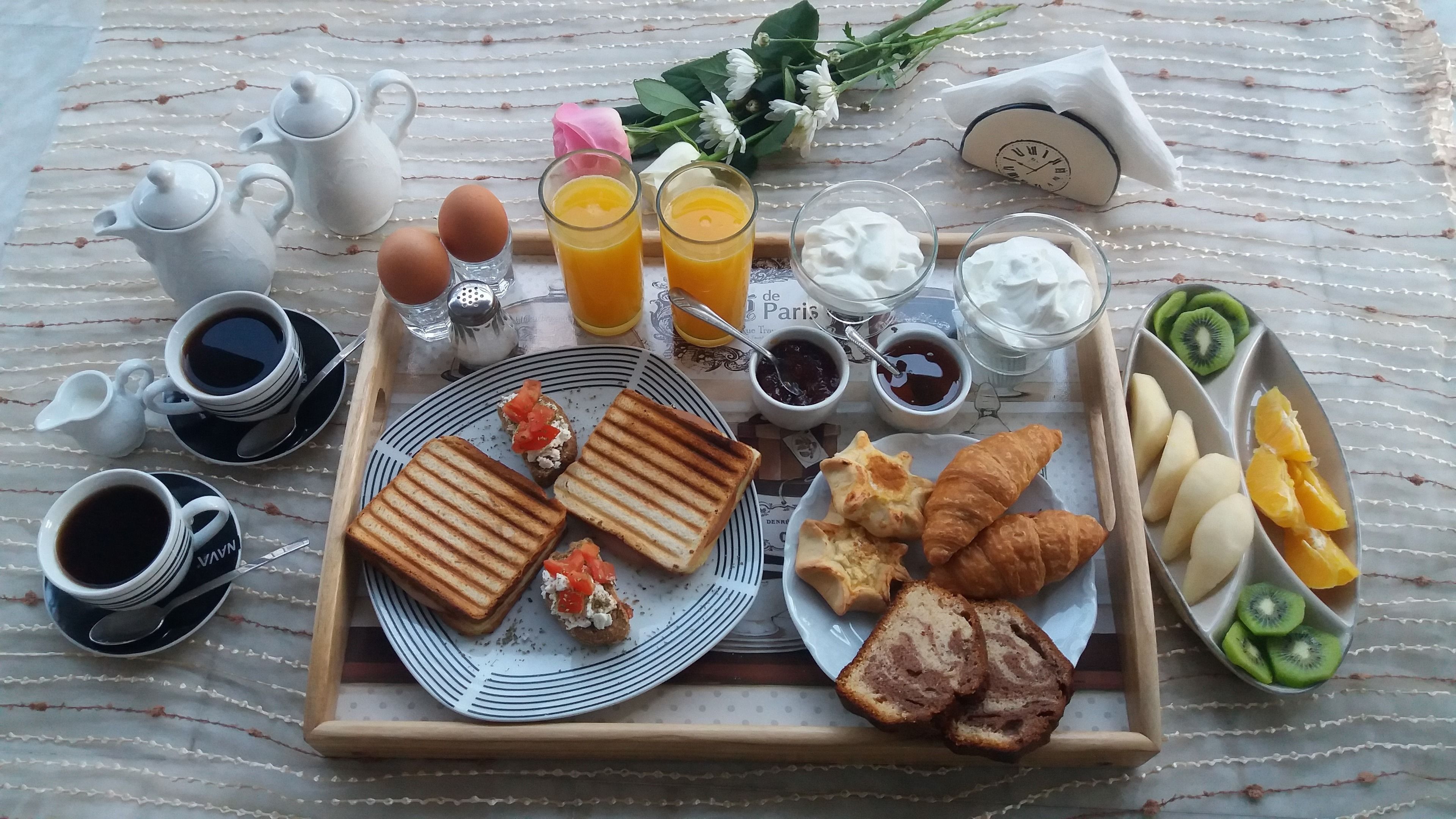 A breakfast tray with toast, croissants, fruit, and beverages.