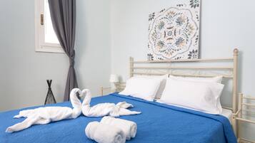 A neatly made bed with blue bedding, white pillows, and two white towels arranged on the bed.