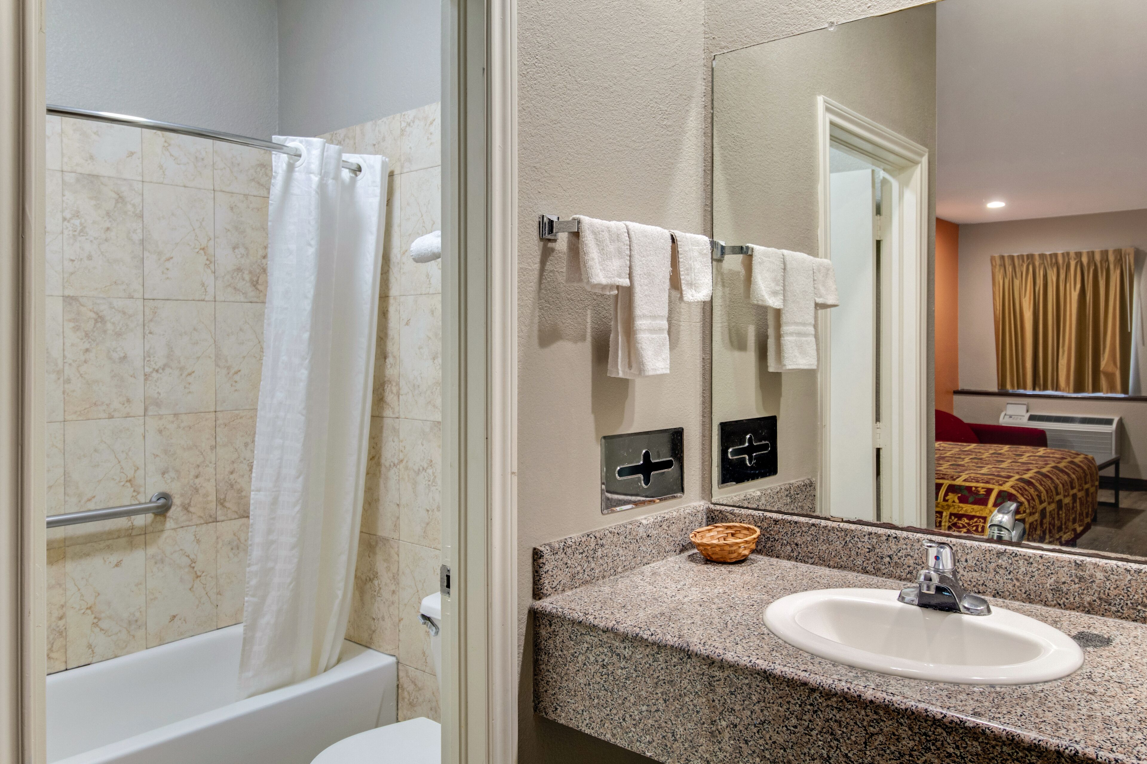 A bathroom with a bathtub, a sink, and a mirror.