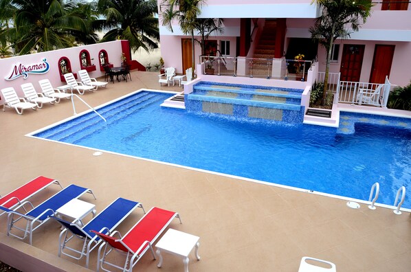 A pool area with lounge chairs and a sign for 'Miramar'.