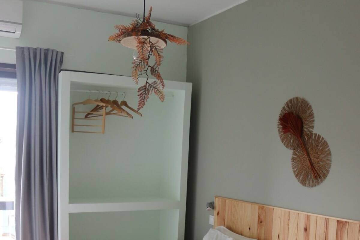A hotel room with two beds, a wooden headboard, a hanging plant, and a wall decoration.