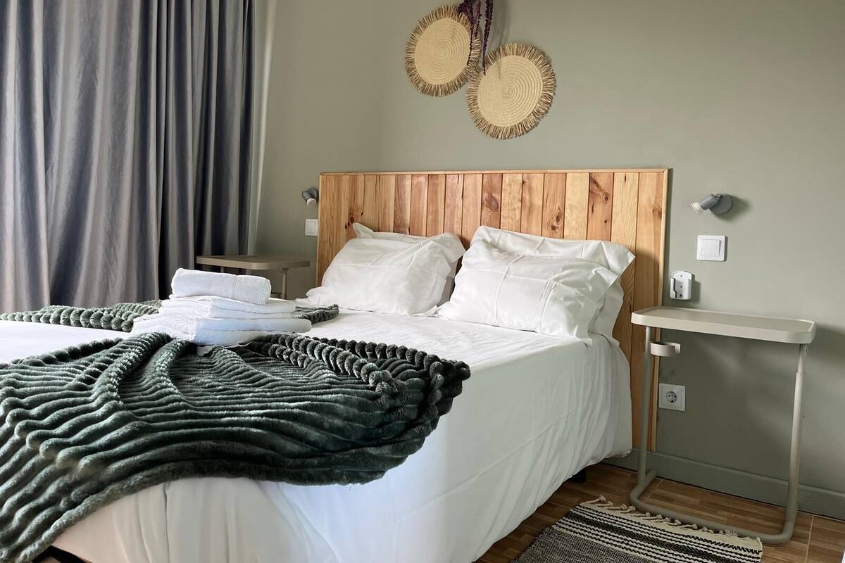 A neatly made bed with white linens, a wooden headboard, and a bedside table with a lamp.