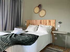 Una cama bien hecha con sábanas blancas, un cabecero de madera y una mesita de noche con lámpara.