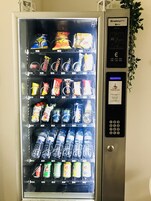 Máquina expendedora con diferentes snacks, bebidas y una interfaz de pago.