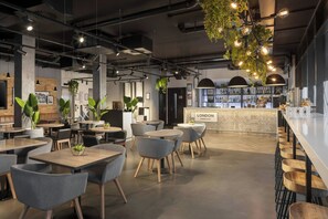 A modern cafe with round tables, grey chairs, and a bar area with a 'LONDON' sign. - Four Points Flex by Sheraton London Shoreditch East (London)