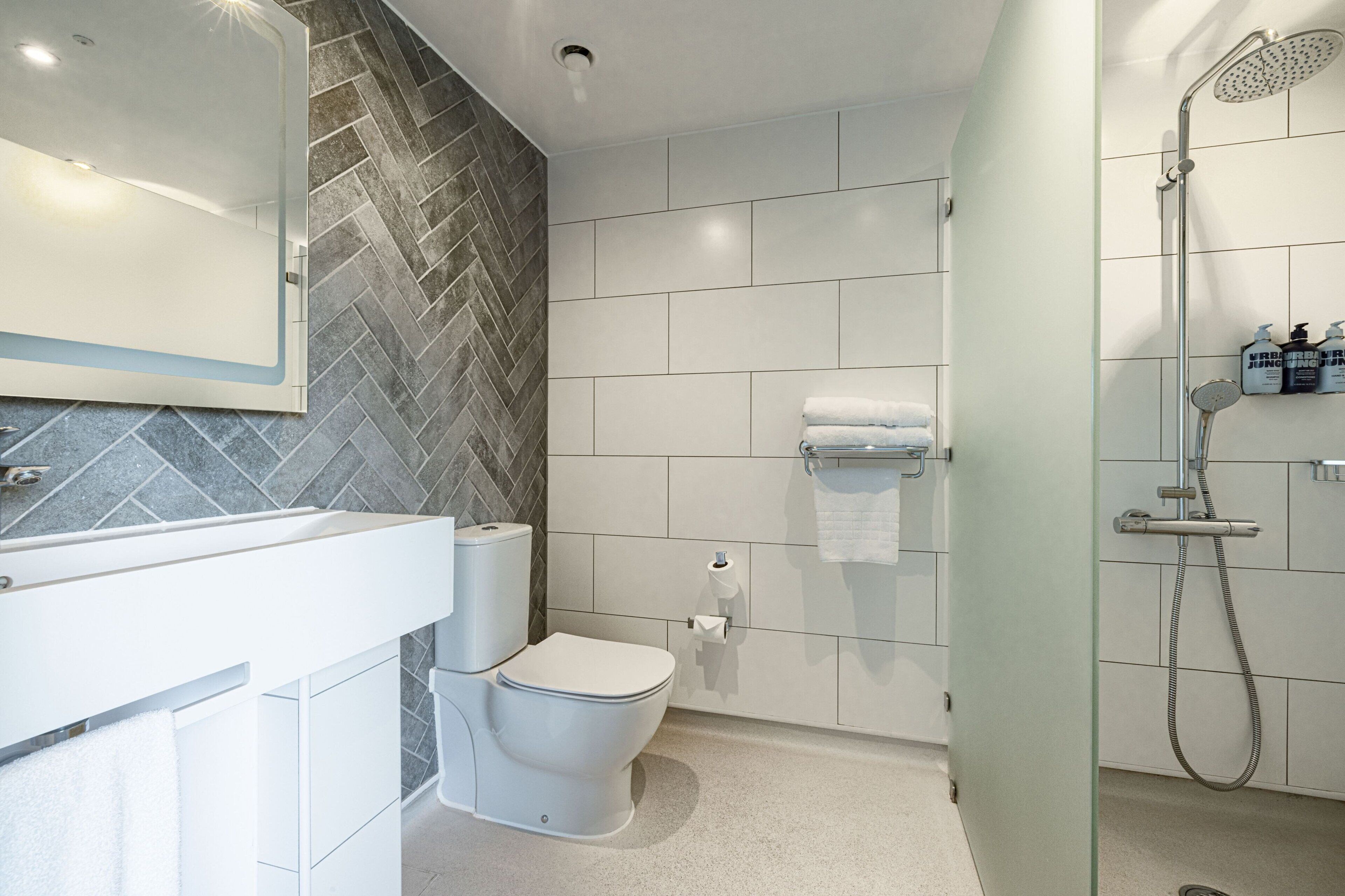 A modern bathroom with a toilet, a shower, and a sink.