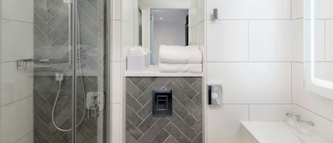 A modern bathroom with a glass-enclosed shower, a white sink, and a mirror.