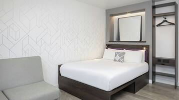 Una habitación de hotel moderna con cama, sofá, espejo y armario.