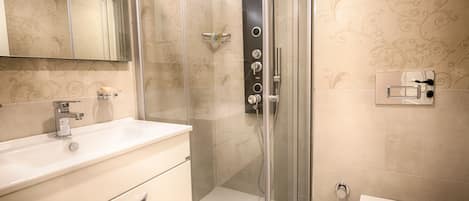 A modern bathroom with a glass-enclosed shower, a white sink, and a mirror above the vanity.