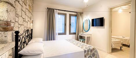A bedroom with a bed, a desk, a mirror, and a TV.