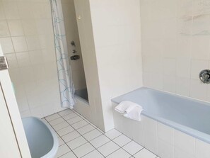 Un baño con bañera, inodoro y zona de ducha.