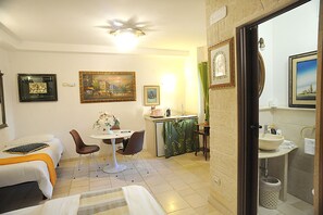A hotel room with a bed, a small dining area with a table and chairs, a kitchenette, and a bathroom with a sink and mirror. - B&B Gianluis (Fasano)