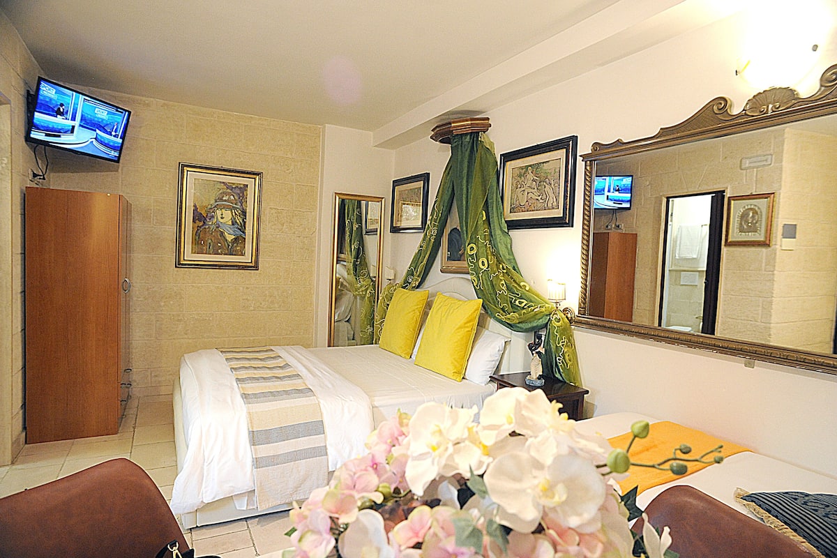 A hotel room with a bed, a television, and a large mirror.