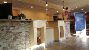 A reception area with a stone wall, a flower vase, and a sign about the lowest price guarantee.