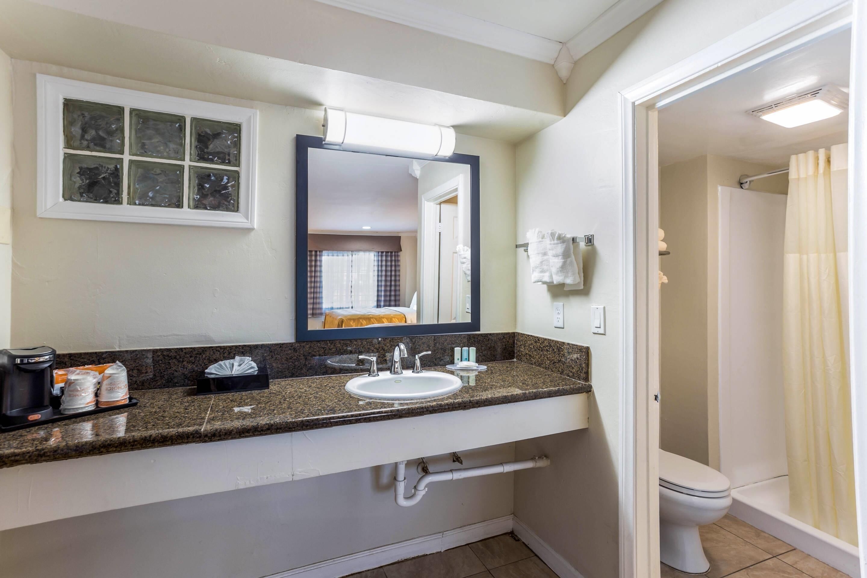 A bathroom with a sink, mirror, and shower.