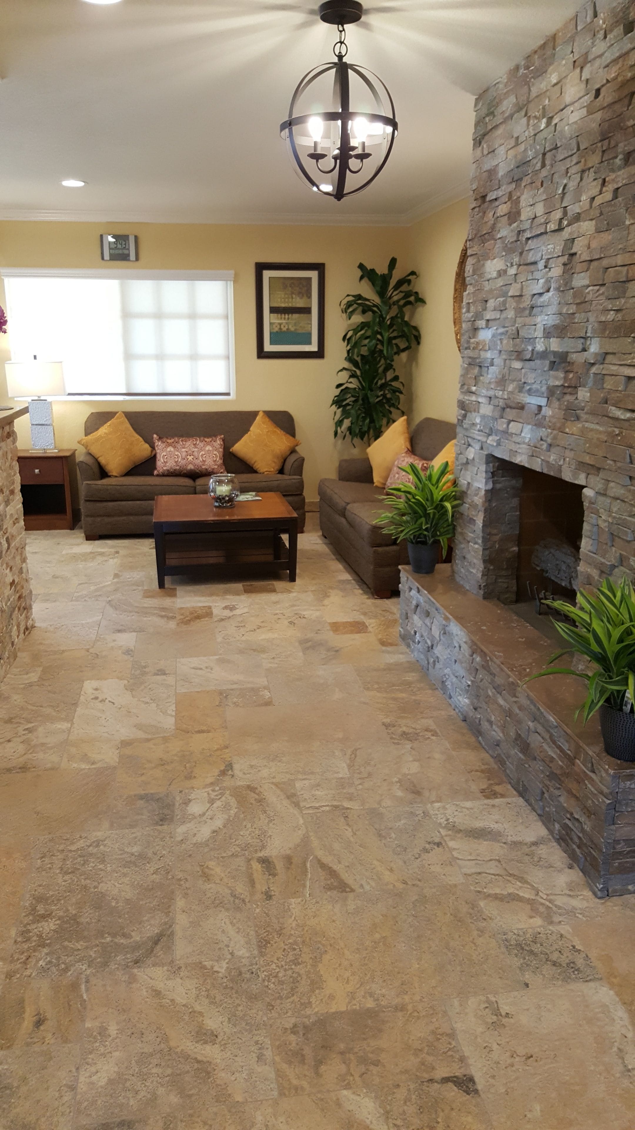 A living room with a stone fireplace, a chandelier, and a sofa with cushions.