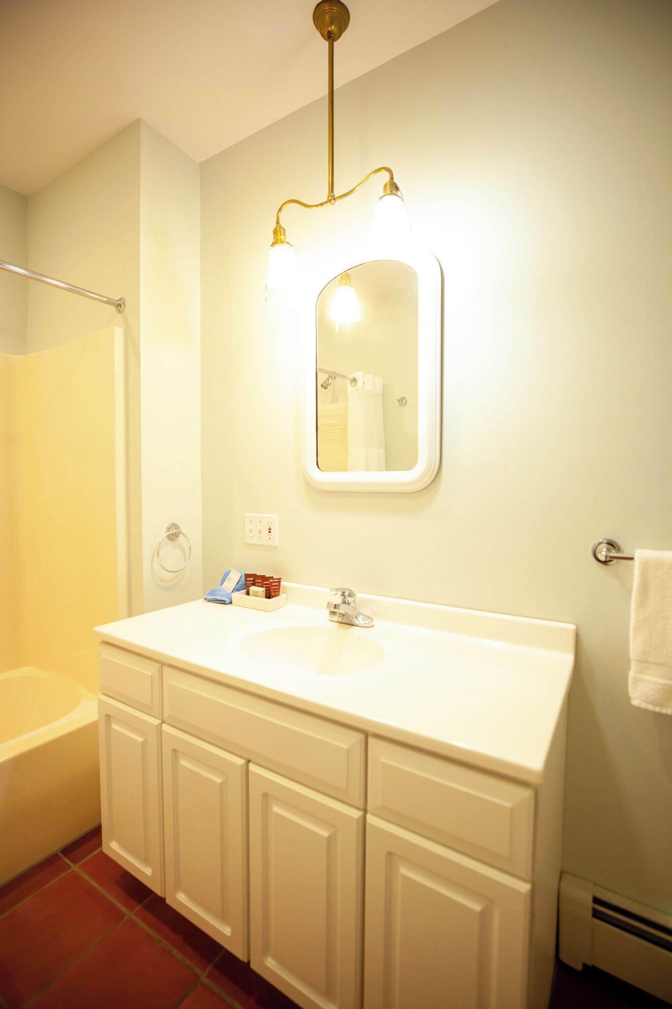 A bathroom with a white sink, mirror, and a shower area.