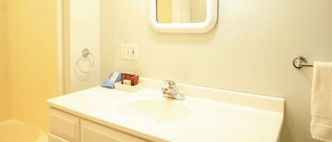 A bathroom with a white sink, mirror, and a shower area.