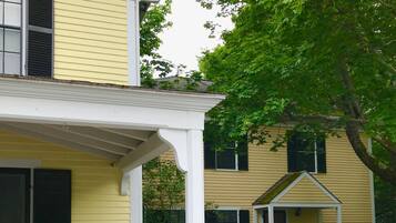 A two-story house with a covered porch, a small attached structure, and a garden path.